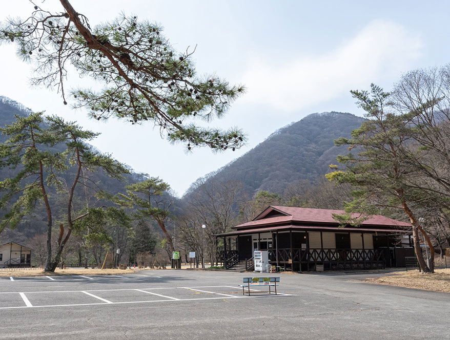 山々に囲まれたキャンプ場の建物。手前には広い駐車場も完備。